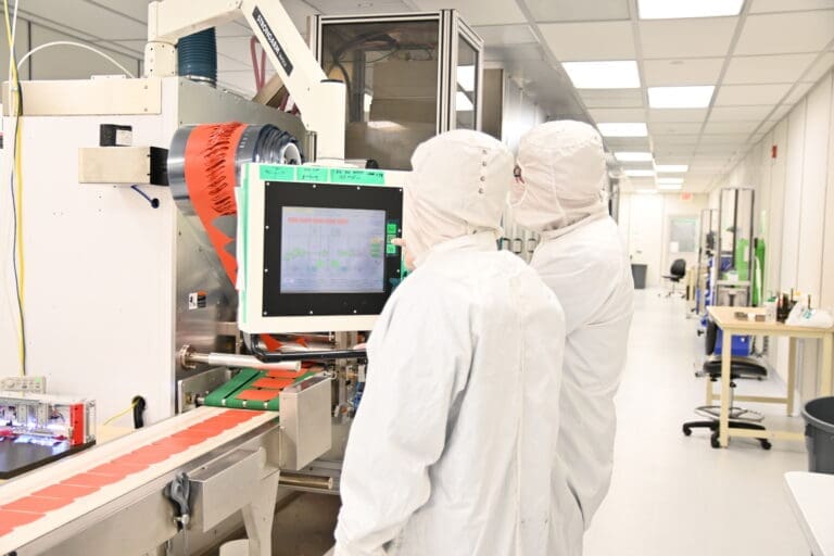 Photo of Technicians Viewing Kent Displays Contract Roll to Part Manufacturing Line